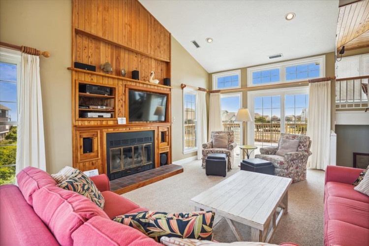 Relax in your spacious living room with soaring vaulted ceilings, a cozy gas fireplace, and abundant natural light streaming through oversized windows overlooking peaceful neighborhood views.