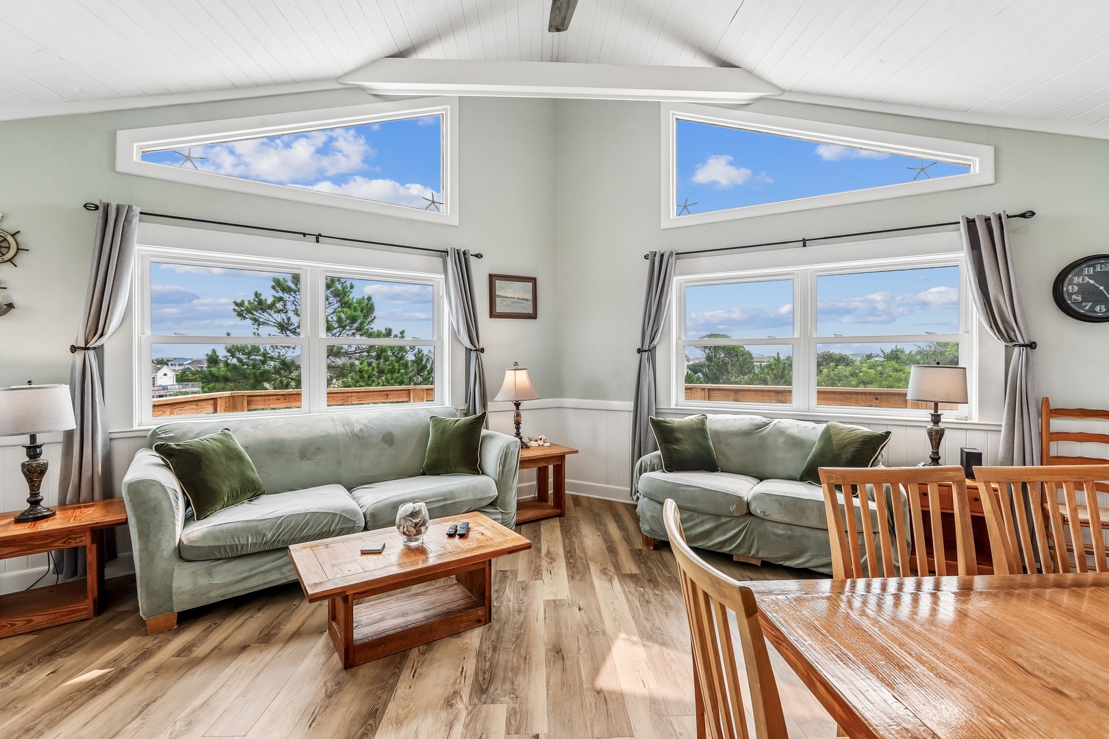 Sink into plush green sofas and gaze through soaring windows that frame stunning lake and tree views, creating your perfect retreat for relaxation and natural beauty.