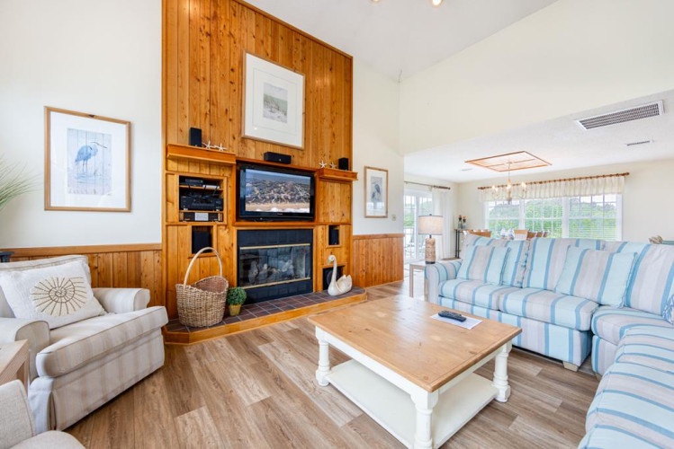 Curl up on soft sofas, watch the fireplace glow, and enjoy your favorite shows in this bright, coastal-chic living room with vaulted ceilings and plenty of space to relax together.