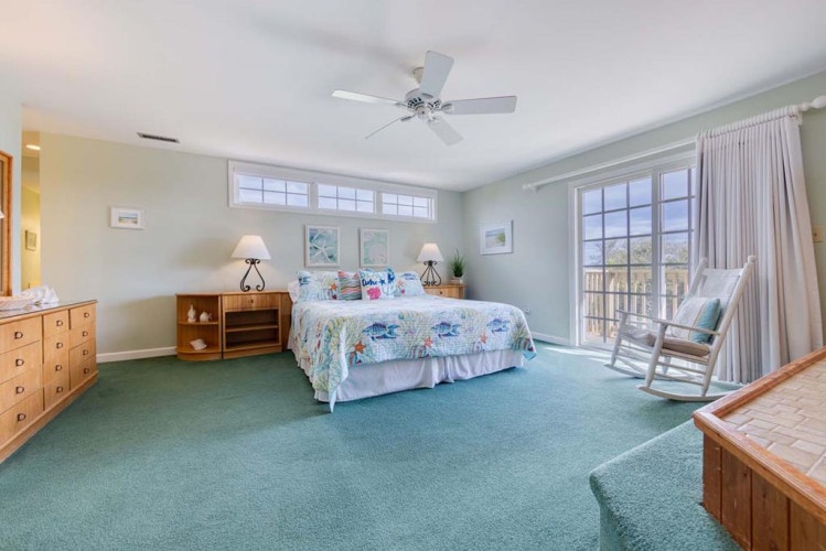 Wake up to soft coastal breezes and natural light flooding through your private balcony doors. Relax in your serene bedroom with calming pastel tones, a cozy rocking chair, and refreshing overhead fan.