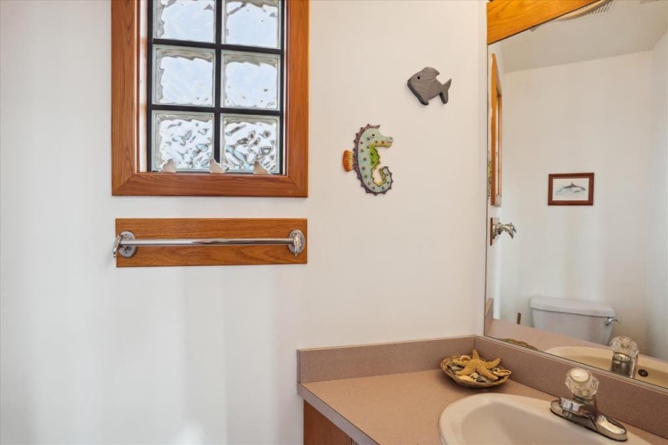 Your private bathroom features a cozy coastal theme with playful sea creature decor and warm wood accents, creating a welcoming retreat after beach adventures.