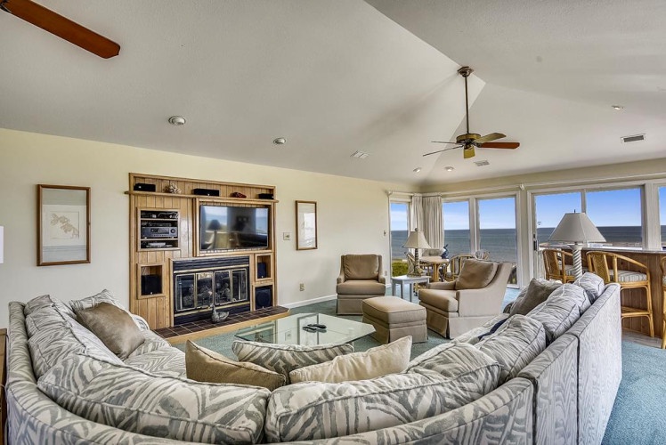 Relax in this spacious living room with sweeping views. Sink into plush sofas, enjoy your favorite shows on the large TV, and soak in natural light pouring through expansive windows overlooking the serene landscape.