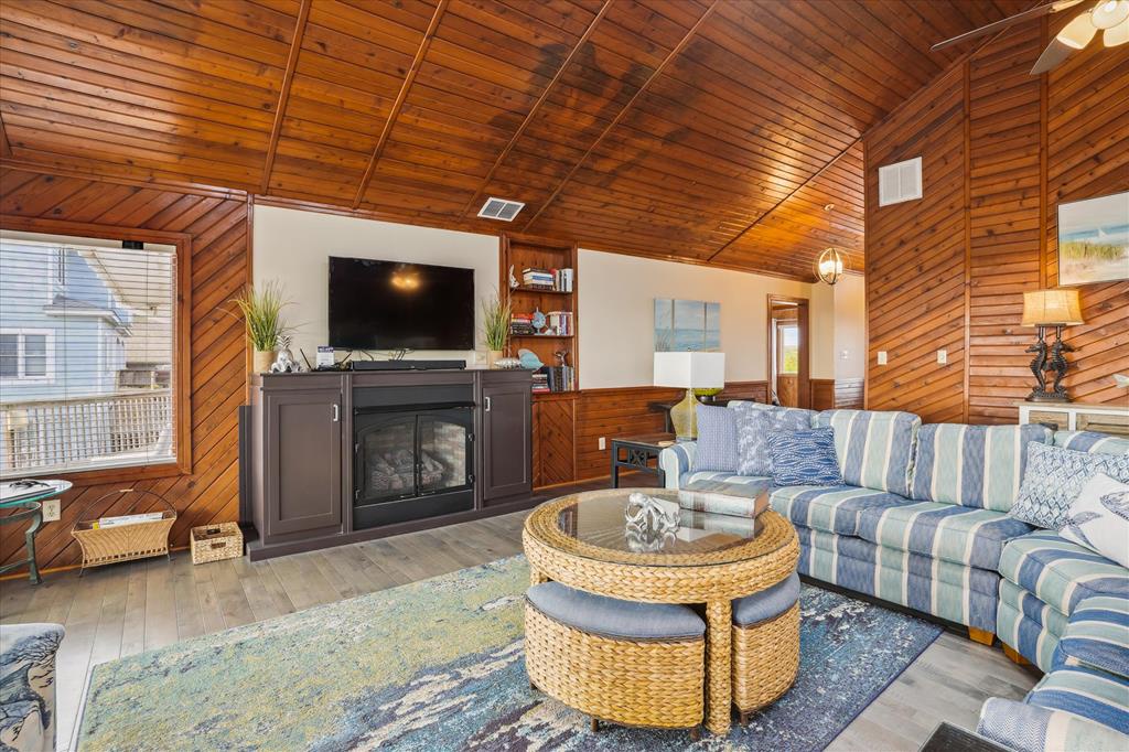 Relax in your cozy living room featuring warm wood paneling, a stylish fireplace, and coastal-inspired décor—perfect for unwinding after a day of adventure.