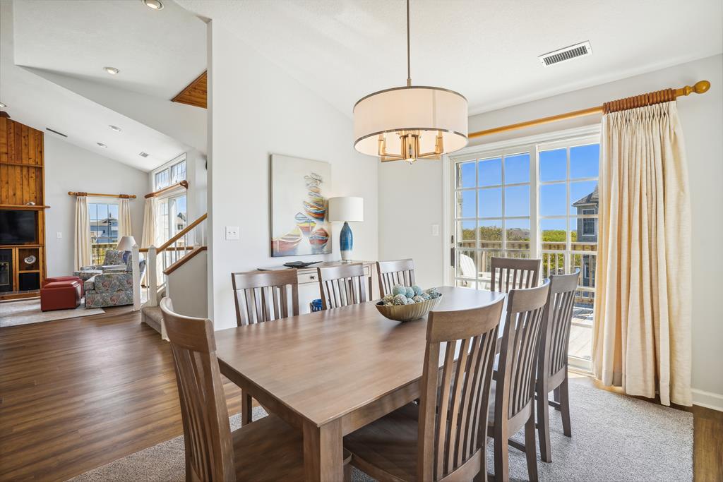 Gather around the spacious dining table for memorable meals bathed in natural light, with coastal breezes and views of neighboring homes just beyond the open deck doors.