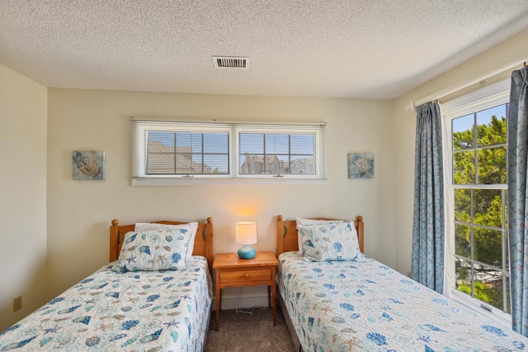 Drift off in this serene twin bedroom where soft ocean-themed linens and calming coastal artwork welcome you. Natural light fills your space, promising restful nights and peaceful mornings.