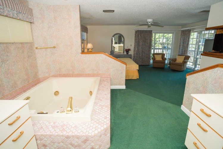 Your spacious suite features an elegant in-room soaking tub with thoughtful tiling, an open layout flowing into a bright living area, and sliding doors welcoming natural light and fresh air.