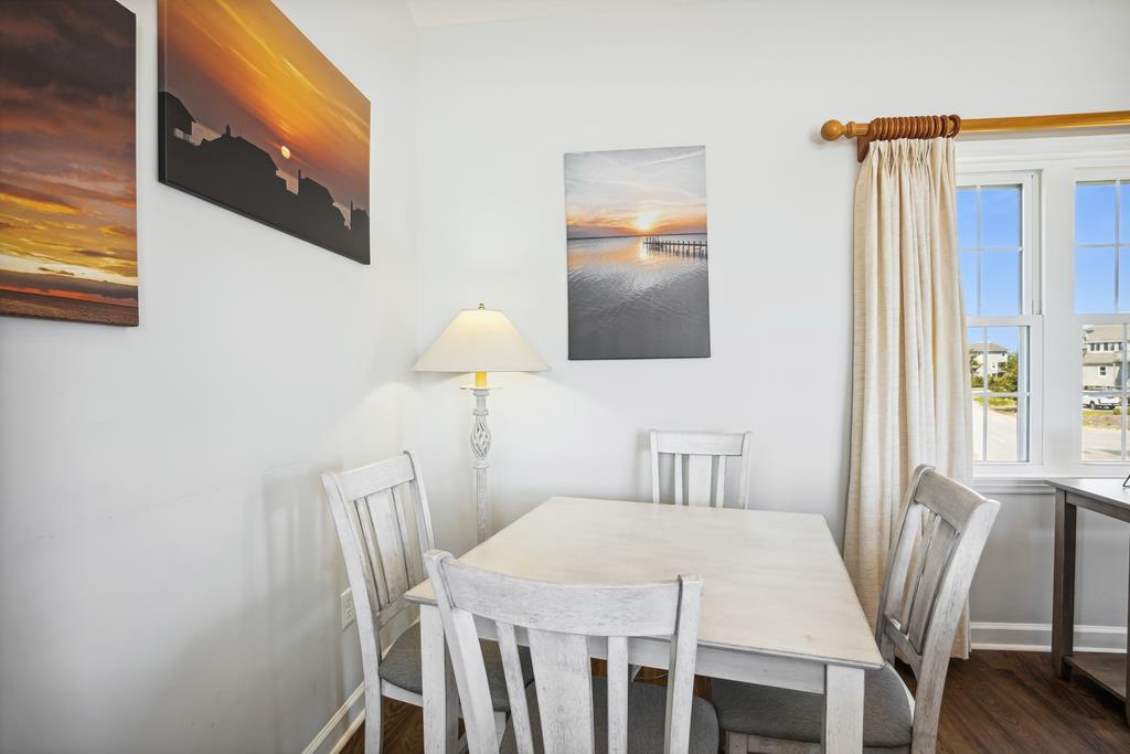 Gather at this charming dining table beneath coastal artwork. Natural light spills in, setting the scene for shared meals and unforgettable moments together.