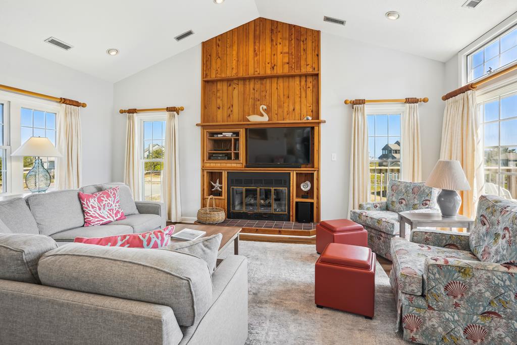 Unwind in this bright, spacious living room with a cozy fireplace, elegant wood-paneled entertainment center, and comfortable seating perfect for gathering with loved ones.