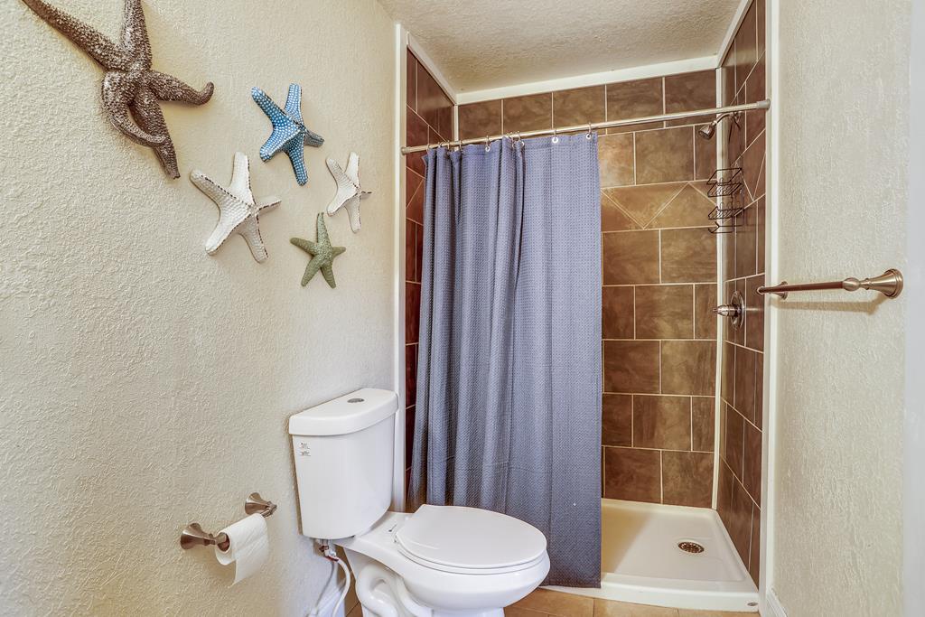 Step into your private bathroom with coastal touches—tiled shower, fresh towels, and charming starfish decor create a beachy retreat after your day exploring.