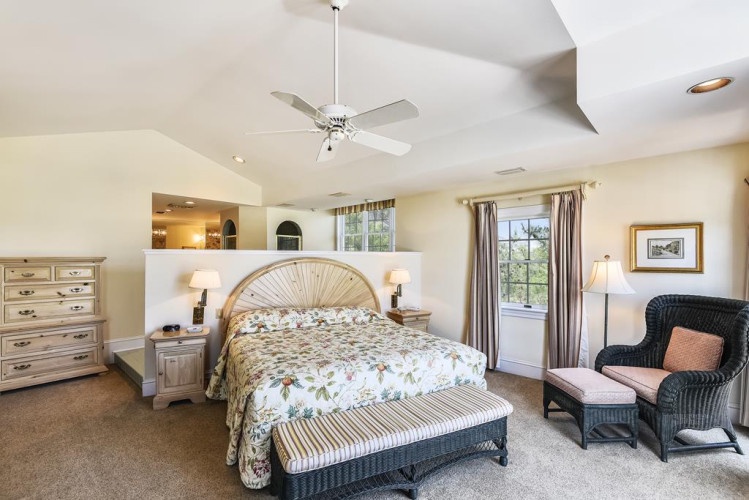Your spacious master suite awaits, with vaulted ceilings, abundant natural light, and peaceful views framed by soft curtains. Relax in the sitting area or drift off in serene comfort.
