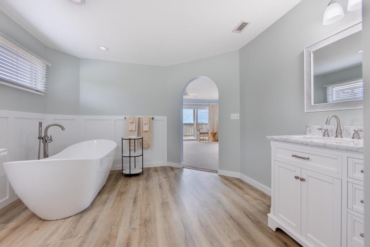 Unwind in your luxurious soaking tub after a day at the beach, with serene coastal views framing your peaceful escape.