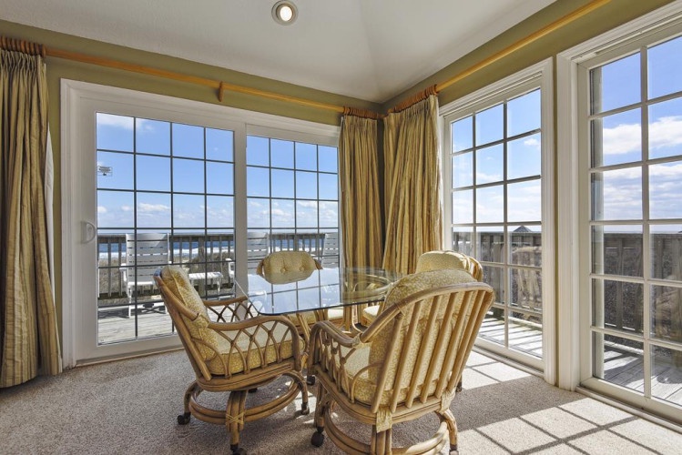 Settle into your sunny seating nook with floor-to-ceiling windows framing uninterrupted water views, where morning coffee or sunset conversations feel like a waterfront escape.