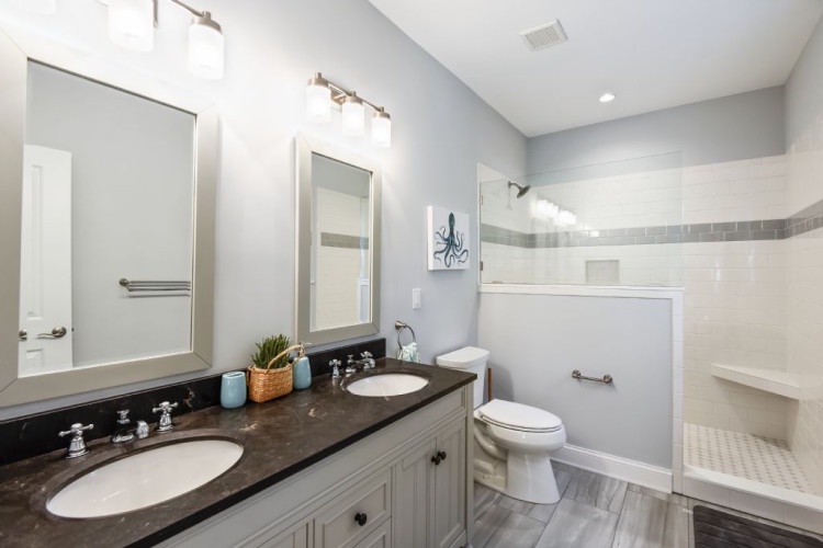 Step into this beautiful bathroom featuring dual vanities, modern fixtures, and a spacious walk-in shower. Fresh towels and thoughtful details await your arrival.