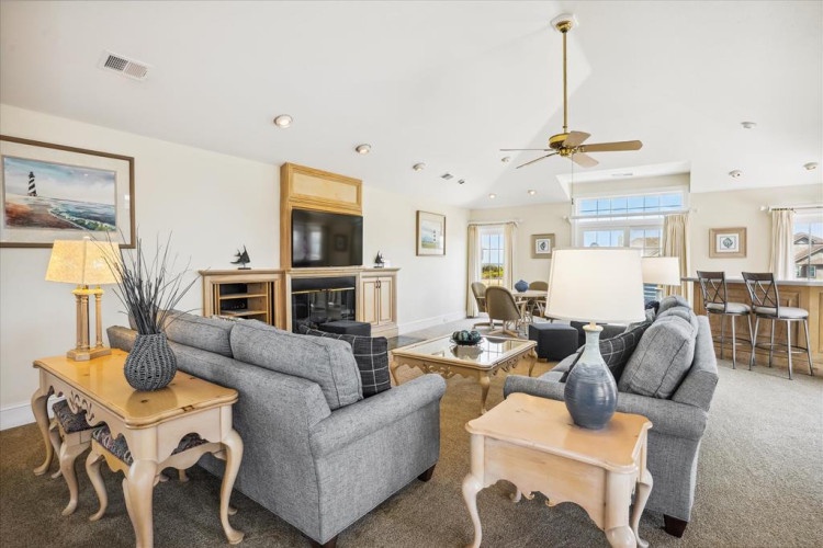 Relax in this bright, open living space where plush gray sofas, coastal accents, and a cozy fireplace create the perfect setting for your family gatherings and evening downtime.