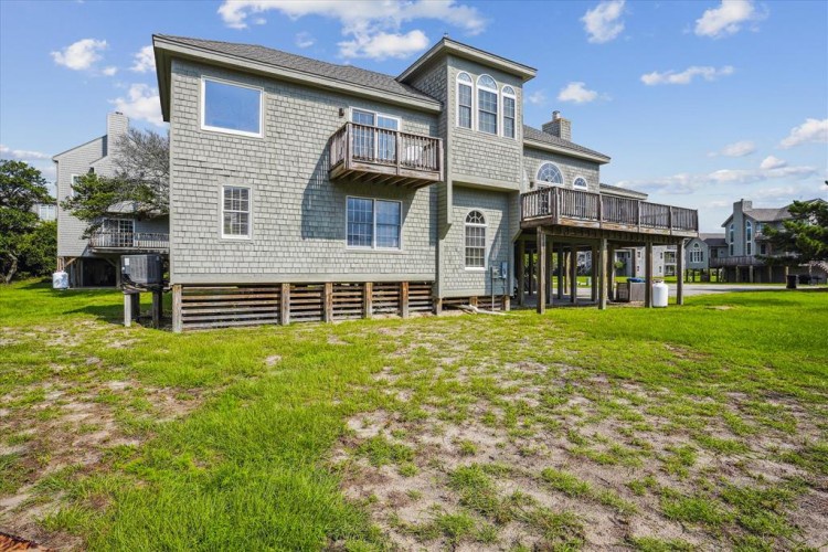 Elevated coastal home with balconies and open yard space, offering easy access to the beach and nearby neighborhood amenities.