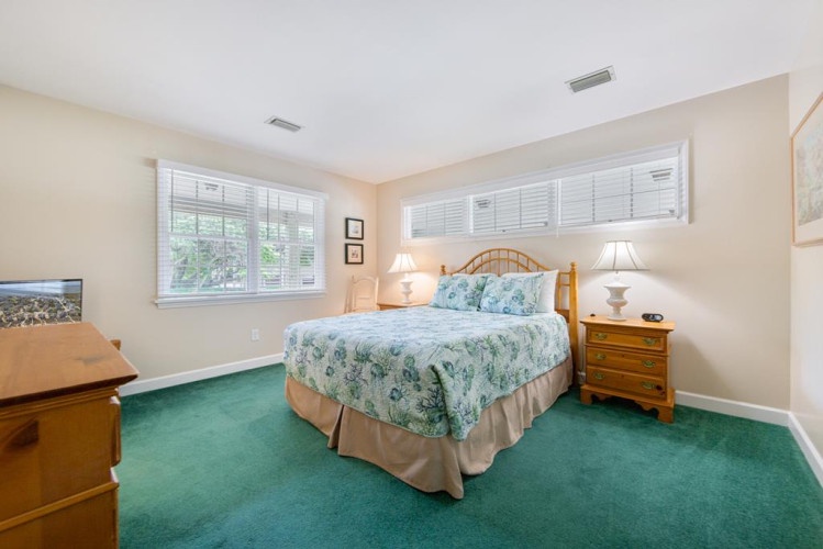 Relax in this peaceful bedroom with soft natural light, a cozy bed dressed in soothing floral linens, and warm wood furnishings creating a welcoming space for restful nights.