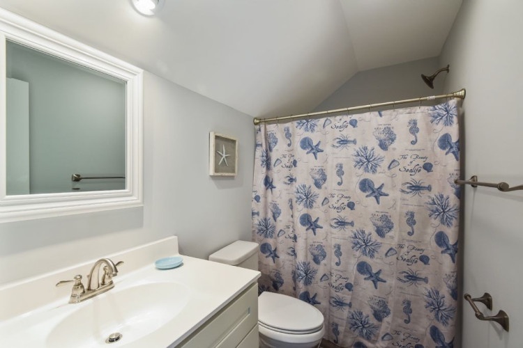 Refresh in this coastal-inspired bathroom, complete with a soothing ocean-themed shower curtain and all the essentials for your comfort.
