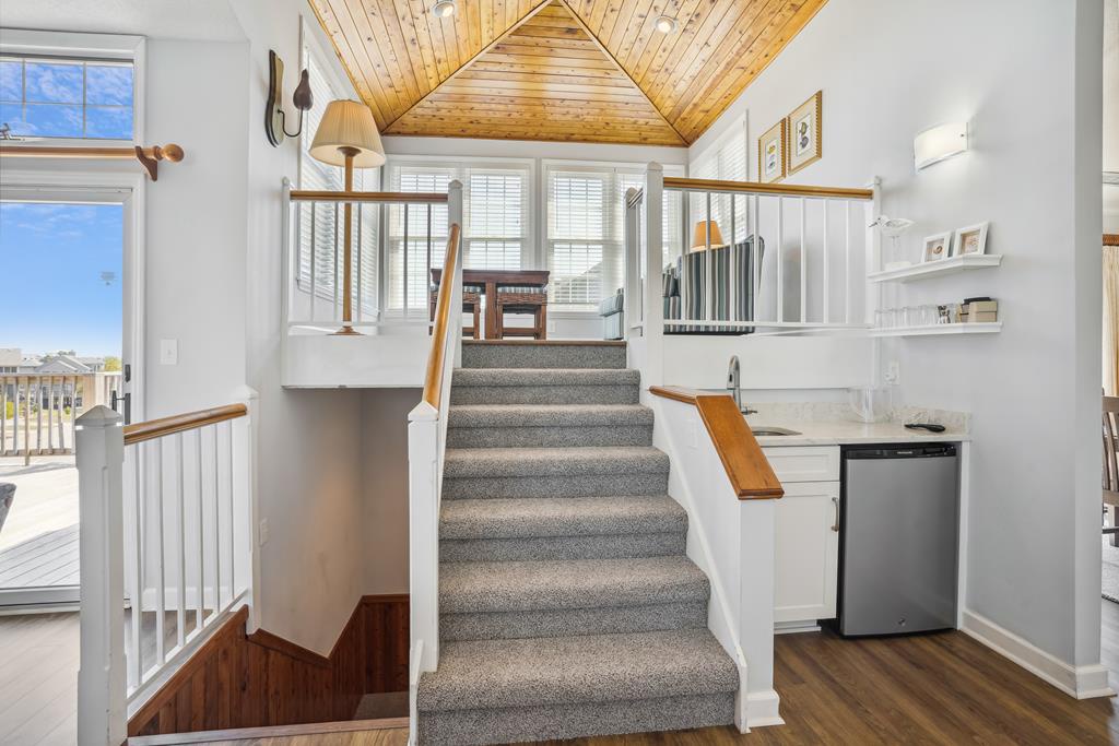 Sunlight streams through the windows, illuminating the vaulted wood ceiling and open layout that connects your cozy living space, compact kitchen, and private loft above—perfect for a peaceful getaway.