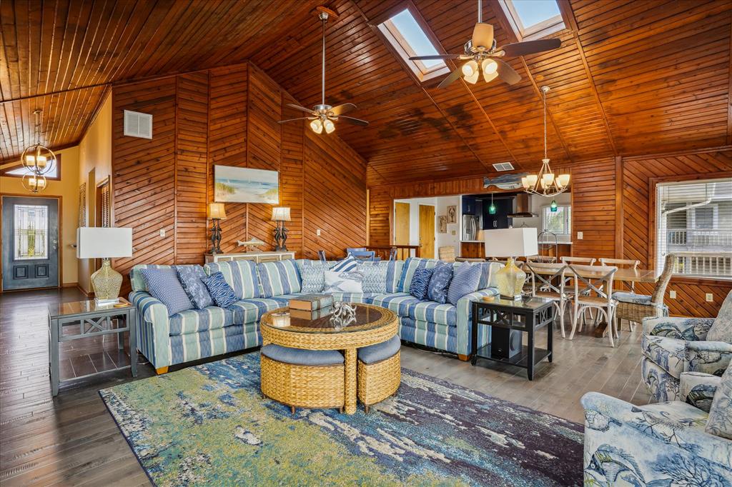 Step into your open-concept haven where rich wood vaulted ceilings and skylights flood the space with warmth. Sink into the striped sectional and feel right at home among coastal accents, inviting you to relax and unwind.