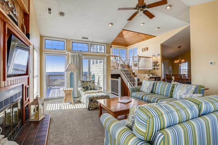 Unwind in this bright, inviting living space where your coastal escape begins. Plush sofas face endless ocean views through floor-to-ceiling windows, while warm wood accents and soaring ceilings create an airy, relaxing retreat perfect for your stay.