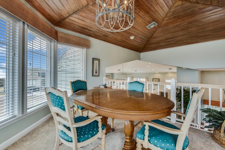 Gather around this inviting wooden table beneath a charming chandelier, where you'll enjoy meals with stunning vaulted wood ceilings overhead and bright windows framing your stay.