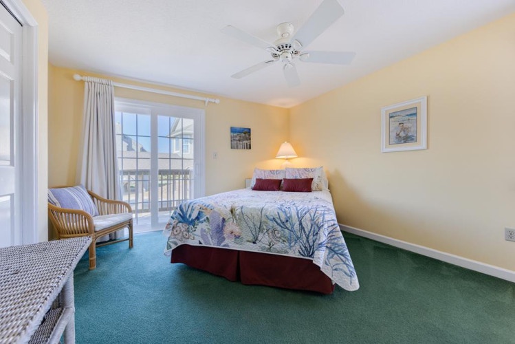 Drift into restful sleep in your bright, coastal-themed bedroom with ocean-inspired linens and natural light streaming through glass doors leading to your private outdoor space.
