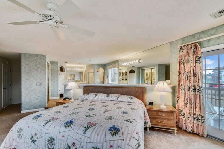 Your spacious bedroom features a comfortable bed, soft lighting, and sliding glass doors opening to a private balcony where you can unwind and take in the view.