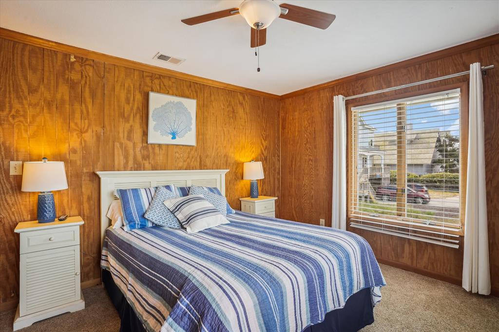 Your cozy bedroom features warm wood walls and coastal blue bedding, inviting you to unwind after a day at the beach.