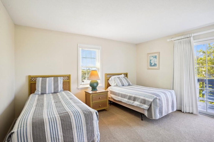 Drift into peaceful sleep in your bright, airy bedroom with twin beds dressed in soft linens, a gentle reading lamp, and sunlit views of the surrounding greenery welcoming you each morning.
