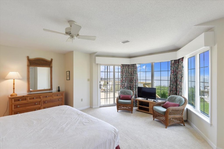 Step into your serene retreat where sunlight pours through expansive windows, framing stunning views. Unwind in cozy seating, enjoy your favorite shows, and feel the ocean breeze as you relax in this peaceful haven.