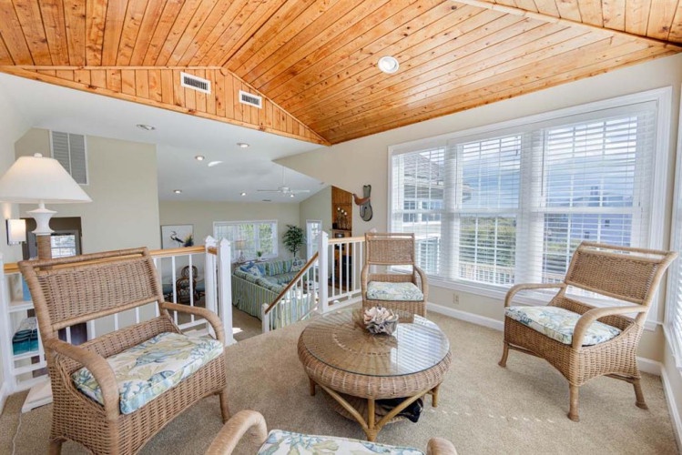 Unwind in your private loft lounge, where cathedral wood ceilings and sunlit windows frame serene views. Sink into wicker seating and let coastal charm embrace you.