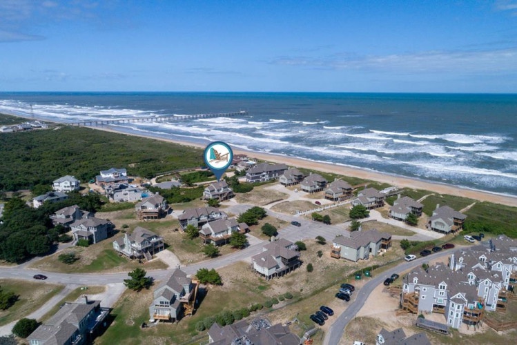 Aerial view of this beachfront coastal property and surrounding residential neighborhood, situated steps from sandy shores and the Atlantic Ocean.