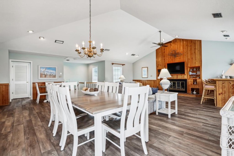 Gather around your spacious dining table under elegant chandelier light, while the cozy living area with wood-paneled fireplace beckons for relaxing evenings together.