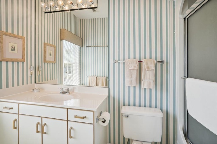 Relax in your private bathroom with coastal charm, featuring fresh towels and a refreshing shower—all the comfort you need after a day at the beach.