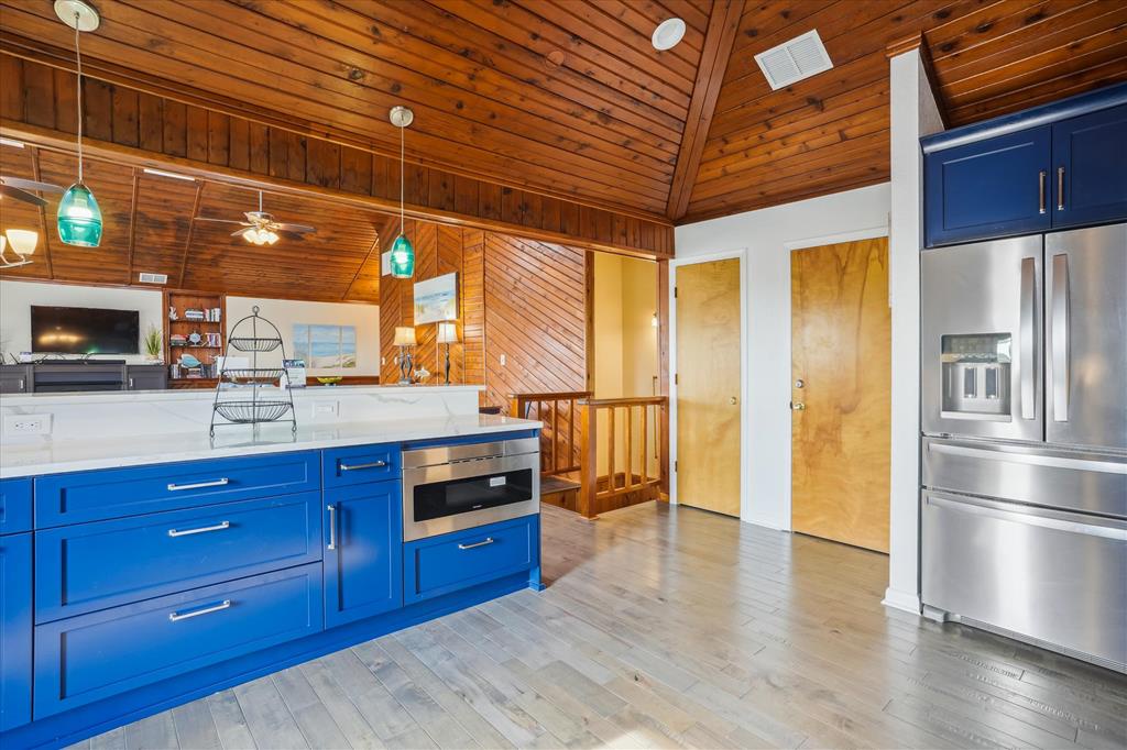 Your spacious, fully-equipped kitchen features bold blue cabinetry and gleaming stainless appliances under warm wood-beamed ceilings—ready for meal prep or morning coffee.