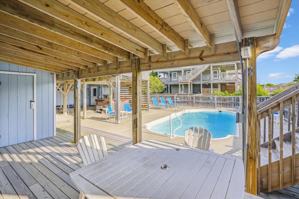 A covered deck overlooking a sparkling pool with lounge chairs awaits your sunny afternoons and poolside relaxation.