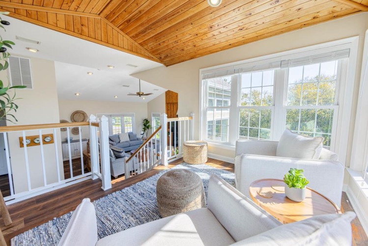 Imagine relaxing in this bright, open space with vaulted wood ceilings and sunlight pouring through large windows. Your peaceful retreat features cozy seating, warm textures, and a welcoming multi-level layout.