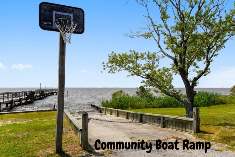 Community boat ramp with basketball hoop, waterfront access, and tree-lined shore. A practical amenity for guests interested in water activities and recreation.