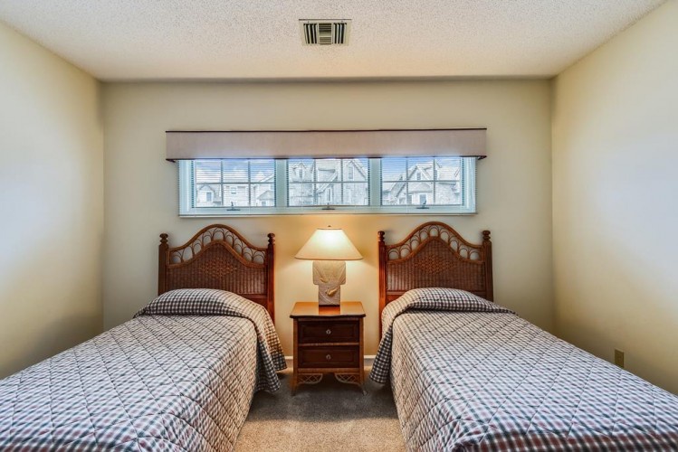 Your comfortable twin bedroom offers two beds with wicker headboards, soft bedding, and warm lighting—ideal for a restful night after exploring the area.