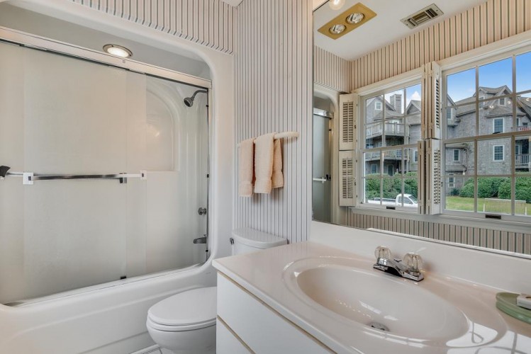 Unwind in your bright, pristine bathroom featuring a luxurious soaking tub, full shower, and charming neighborhood views through the window—perfect for refreshing after a day of adventure.