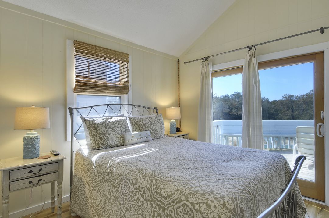 Wake up refreshed in this serene bedroom featuring a cozy queen bed, soft natural light, and private balcony access overlooking peaceful treetops—your personal retreat awaits.