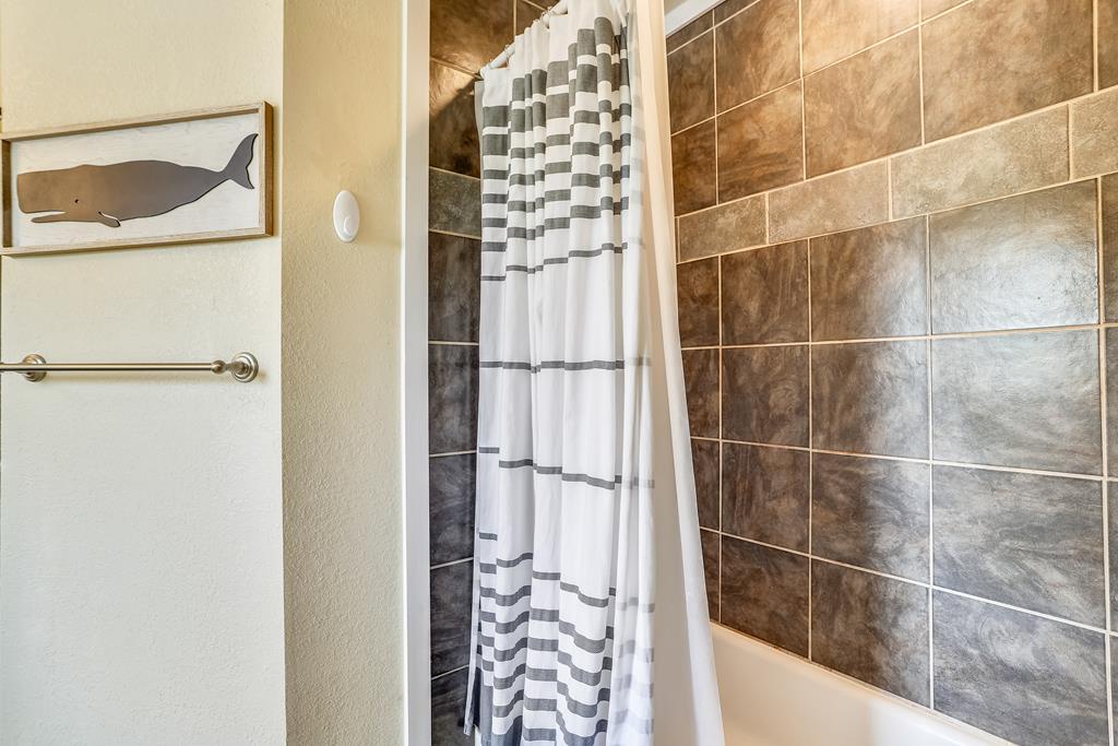 Step into your private bathroom featuring modern tiled walls and a sleek shower. Fresh linens and coastal charm create a relaxing retreat after your day exploring.