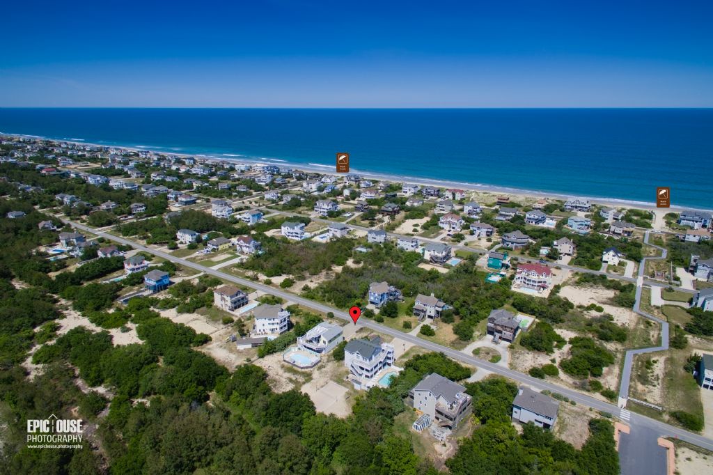 Aerial view of a coastal neighborhood with vacation homes nestled among sandy lots and greenery, just steps from pristine beaches and turquoise Atlantic waters.