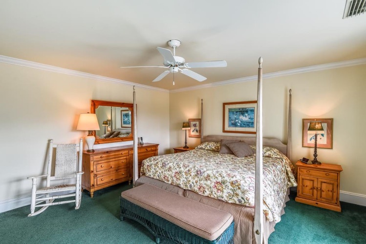 Unwind in your peaceful bedroom, where coastal artwork and a charming four-poster bed invite restful nights. Gentle lighting and classic wood furnishings create a warm, welcoming retreat.