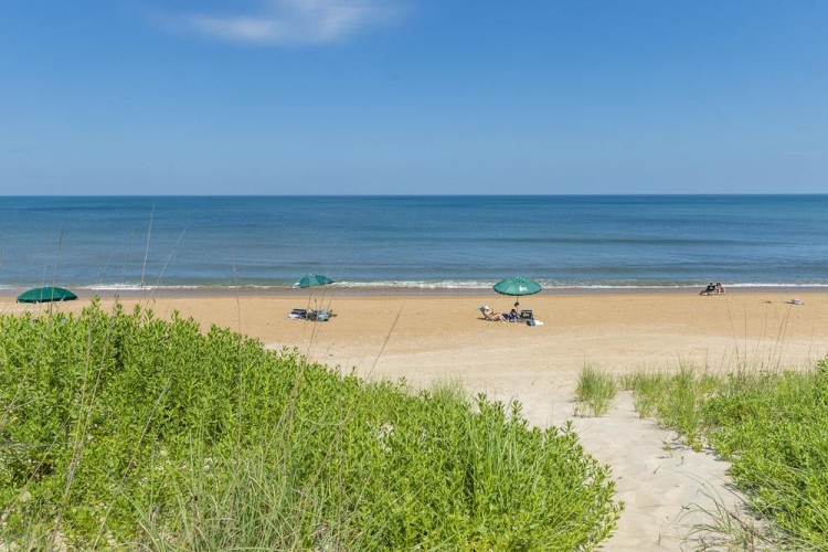 A serene beachfront location with sandy shores and calm ocean waters, offering direct access to a peaceful coastal retreat.