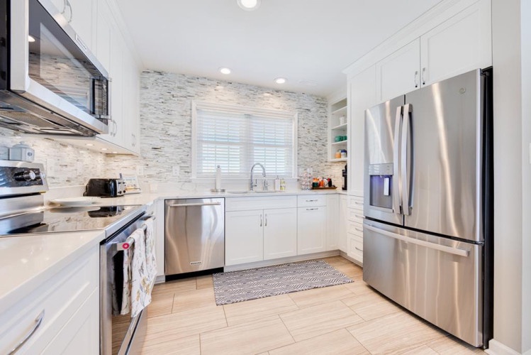 Cook your favorite meals in this bright, modern kitchen with sleek stainless steel appliances, elegant tile backsplash, and plenty of counter space to prepare everything you need.