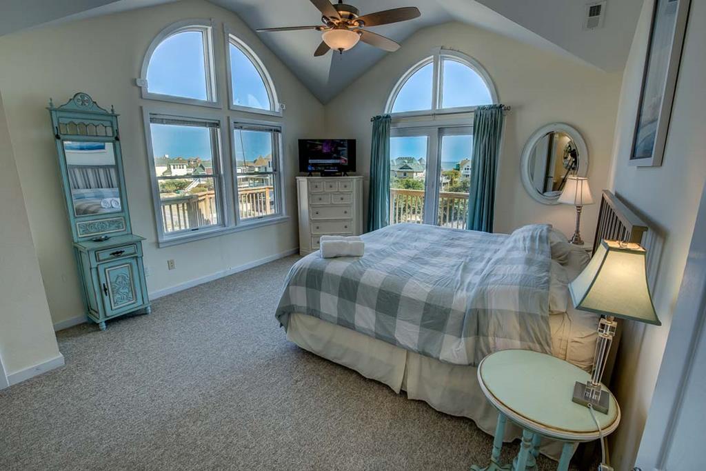 Wake up to stunning ocean views through elegant arched windows in your serene coastal bedroom. Soft breezes from your ceiling fan and plush bedding ensure your perfect beach retreat.