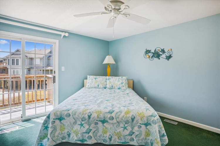 Your tranquil bedroom retreat with coastal décor, a cozy queen bed, and a private balcony offering sunny neighborhood views—perfect for your morning coffee.