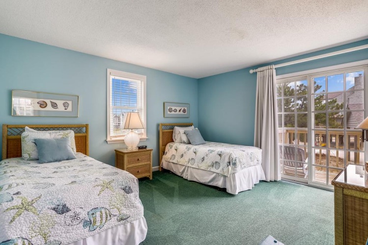 Soothing coastal colors embrace two comfy beds with beach-themed linens. Soft light fills the space while your private balcony invites morning coffee with views of swaying palms.