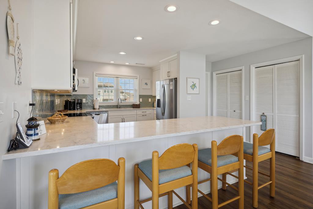 Your open-concept kitchen invites gathering, featuring gleaming marble countertops perfect for preparing meals and sharing stories over morning coffee at the breakfast bar.